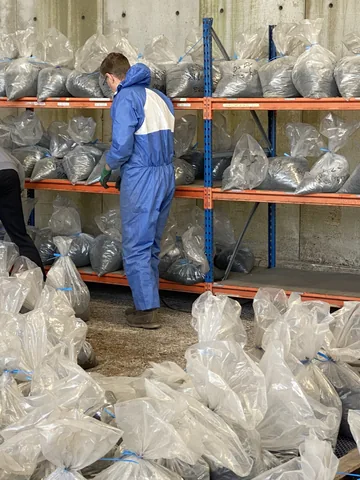 A team member working beside shelves and bagged samples.