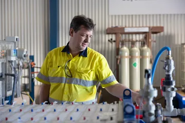 A team member in high-visibility workwear at the pilot equipment controls.