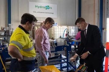 Visitors and a team member examining a sample beside the pilot system.